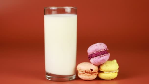 Glass of milk and macaroon on brown background - Footage, Video