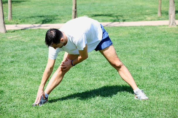Man stretching muscles at the city park. - 写真・画像