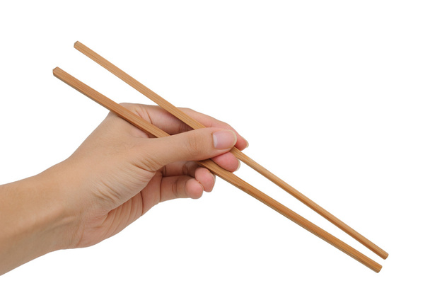 Uso de palillos de bambú con la mano izquierda sobre fondo blanco
 - Foto, Imagen