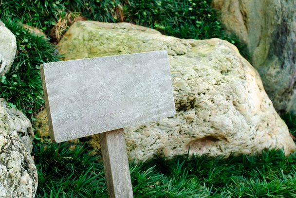 Letrero de madera contra hierba y fondo de roca
 - Foto, Imagen