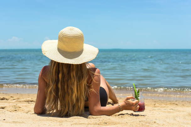 The photo of the beautiful healthy lady in a white hat and black imposing of bikini on sand, a surprising landscape of the sea, is cooled, summer develop the woman, water-melon juice, pink style - Foto, imagen