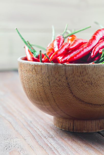 červená chilli paprika v dřevěné míse na dřevěném stole - Fotografie, Obrázek