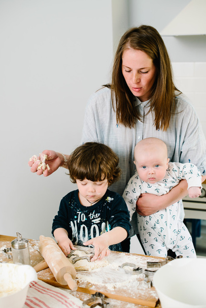 Nuori ja onnellinen äiti lastensa kanssa keittiössä kokki eväste
 - Valokuva, kuva
