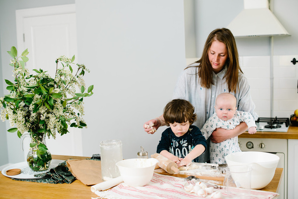 Jovem e feliz mãe com seus filhos na cozinha cozinhar biscoito
 - Foto, Imagem