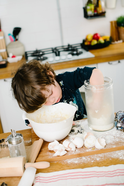 Mały chłopak pomagając matce z pieczenia w kuchni sta - Zdjęcie, obraz