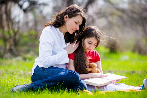 Ευτυχισμένη μαμά και κόρη διαβάζοντας ένα βιβλίο στη φύση - Φωτογραφία, εικόνα