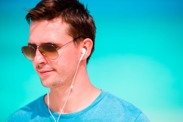 Hombre feliz disfrutando de la música en la playa de arena blanca
 - Foto, Imagen