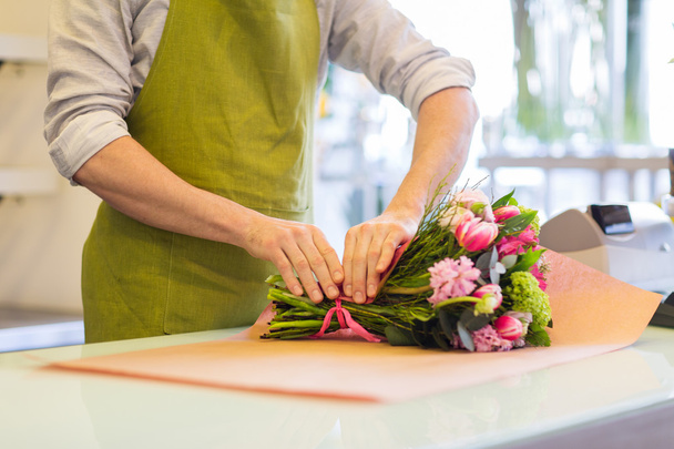 florist wrapping flowers in paper at flower shop - Foto, Bild