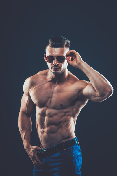 strong athletic man  in sunglasses on black background - Photo, Image