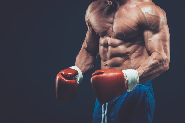 Muscular boxer in studio shooting, on black background. - Zdjęcie, obraz