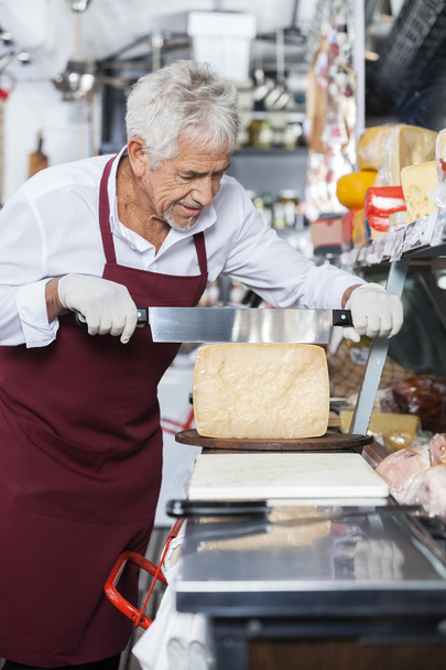Salesman Slicing Cheese With Knife In Shop - Photo, Image