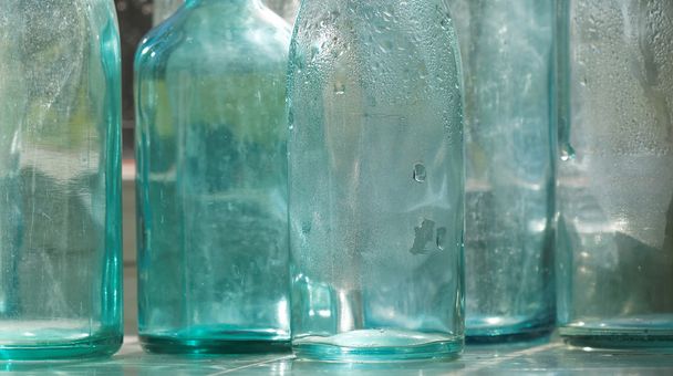 Groupe de bouteilles en verre vides rétroéclairées bleues et transparentes à l'ancienne dans une fenêtre, gros plan
 - Photo, image