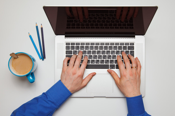 Обрезанное изображение молодого человека, работающего дома над своим ноутбуком, вид сверху на руки бизнесмена, занятого ноутбуком на рабочем столе
 - Фото, изображение