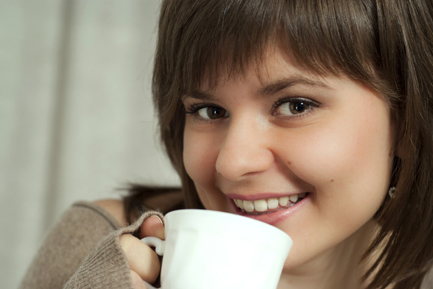 Charming beautiful woman holds a cup - Фото, изображение