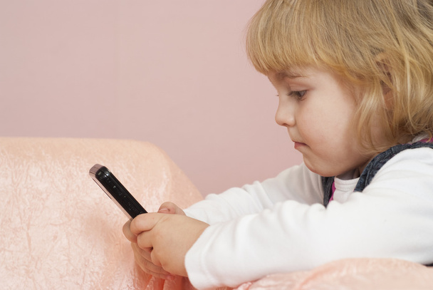 Beautiful little girl playing with the phone - Фото, зображення