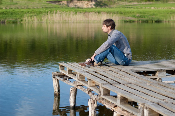 湖の桟橋に腰掛けていた男 - 写真・画像