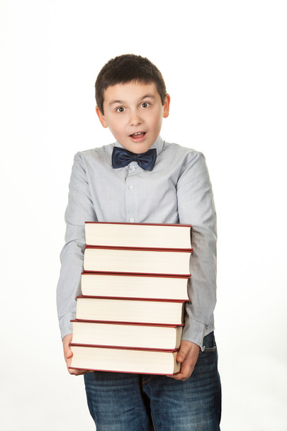 Portrait of a young boy, child, upset, holding six heavy red book - Photo, Image