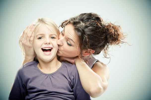 Beautiful brunette woman with young blond girl on grey background - Fotó, kép