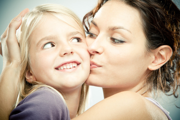 Beautiful brunette woman with young blond girl on grey background - Фото, зображення
