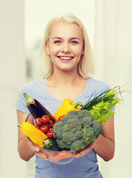 smiling young woman with vegetables at home - Foto, immagini