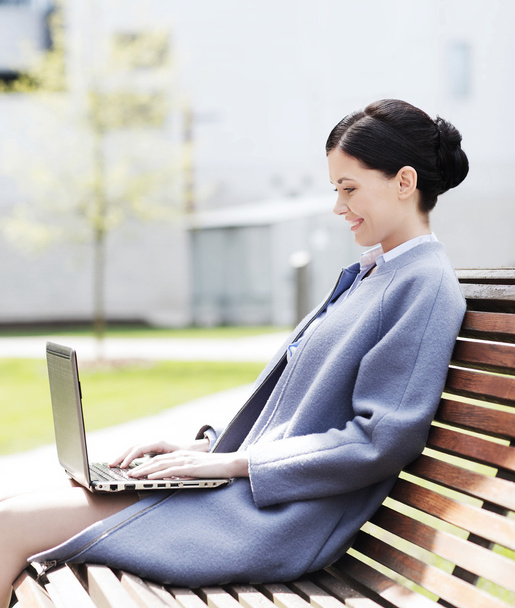 smiling business woman with laptop in city - Foto, Bild