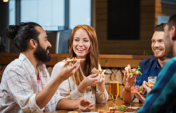 friends eating pizza with beer at restaurant - Photo, image