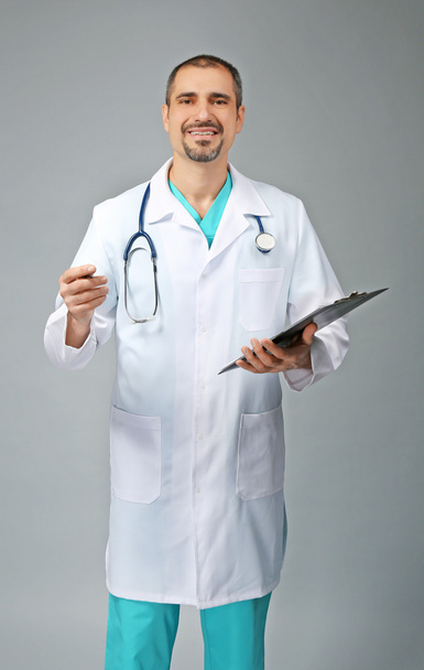 Портрет врача с доской рецепта в руках на сером фоне
 - Фото, изображение