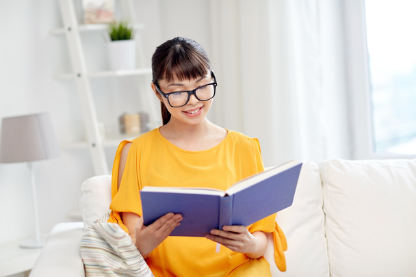smiling young asian woman reading book at home - Фото, изображение