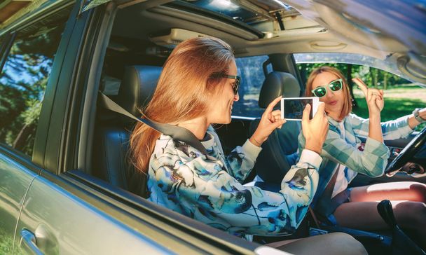 Woman taking photo to her friend inside of car - 写真・画像