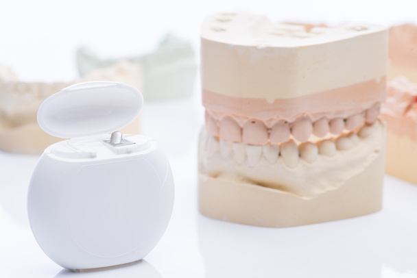 Mallen van de tanden met tandzijde op een helder witte tafel - Foto, afbeelding