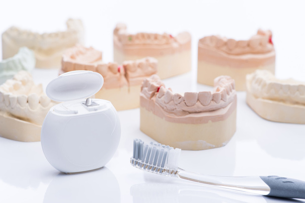 Зубні форми з зубною ниткою і пензлем на яскраво-білому столі
 - Фото, зображення