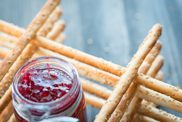 Bunch of homemade grissini breadsticks in a glass jar on wooden surface - Photo, Image