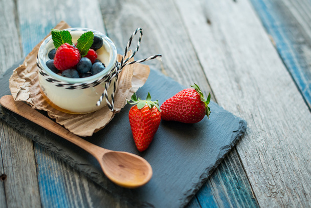 Yogur natural fresco y saludable con bayas en la mesa de madera
 - Foto, imagen