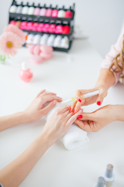 Woman in salon receiving manicure by nail beautician - Fotó, kép