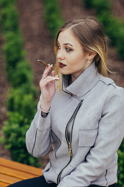 Young woman smoking cigarette on the bench - Foto, imagen