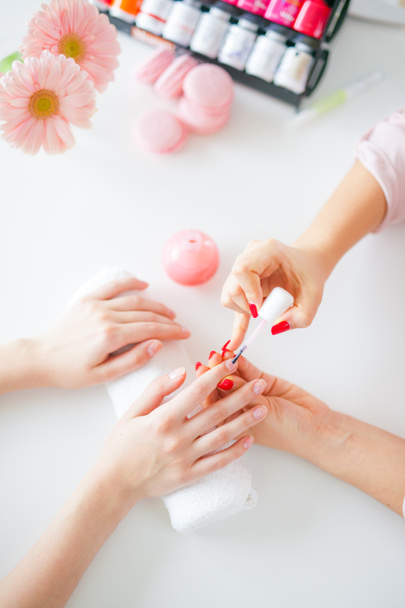 Woman in salon receiving manicure by nail beautician - Fotoğraf, Görsel