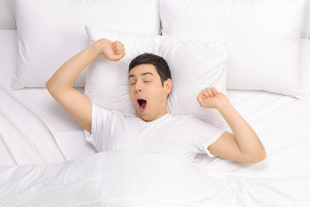 Отдыхающий мужчина просыпается в постели
  - Фото, изображение