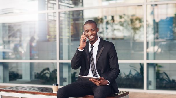 businessman smiling on city bench with phone - Foto, Bild