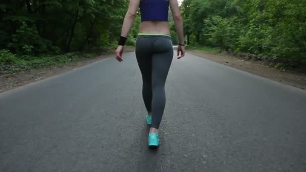 Dziewczyna, chodzenie na drodze w lesie. fitness na świeżym powietrzu. strzał z steadicam - Materiał filmowy, wideo