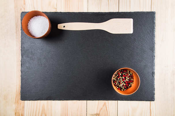spices and a wooden spatula on a blackboard, a top view - Foto, Imagem