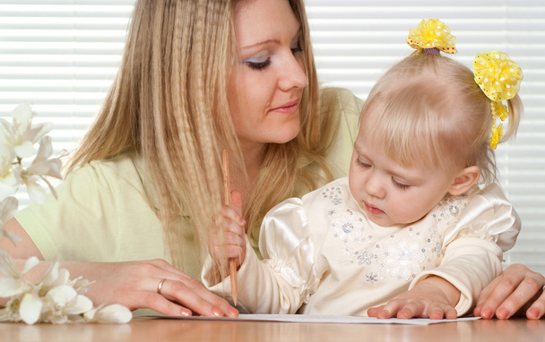 Красивая белая мать и счастливая дочь, сидящая за столом
 - Фото, изображение
