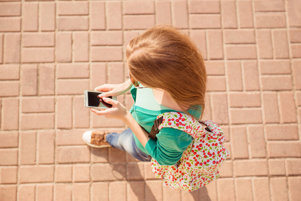 Top view of girl walking on paving stone and typing sms - Valokuva, kuva