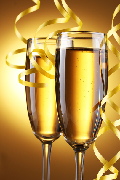 Glasses of champagne and streamer on yellow background - Photo, Image