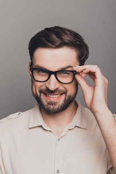 Portrait of attractive happy young man in glasses on gray backgr - Foto, Imagem