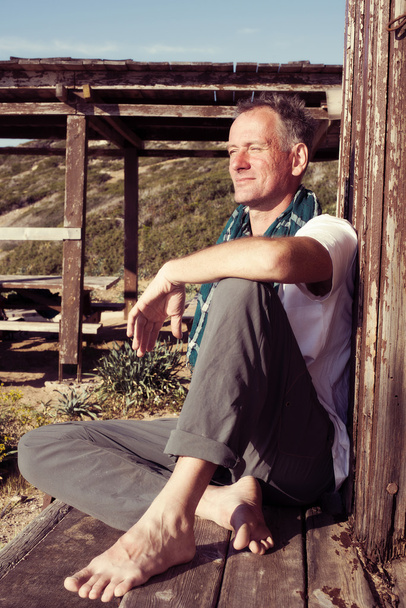 Smiling man sitting on the coast  - Fotografie, Obrázek