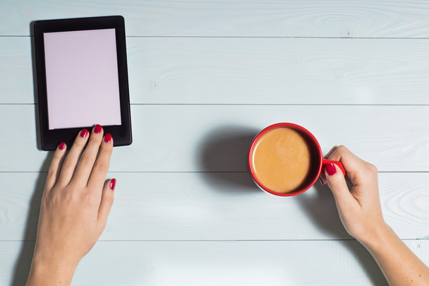Mujer sentada, leyendo e-book y las manos sostienen la taza de café, la puesta plana
. - Foto, imagen