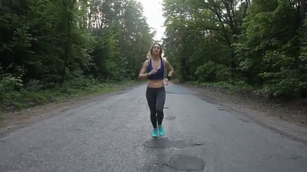 Läuferin läuft auf Straße im Wald. Fitness im Freien. Schuss mit Schwebestativ - Filmmaterial, Video