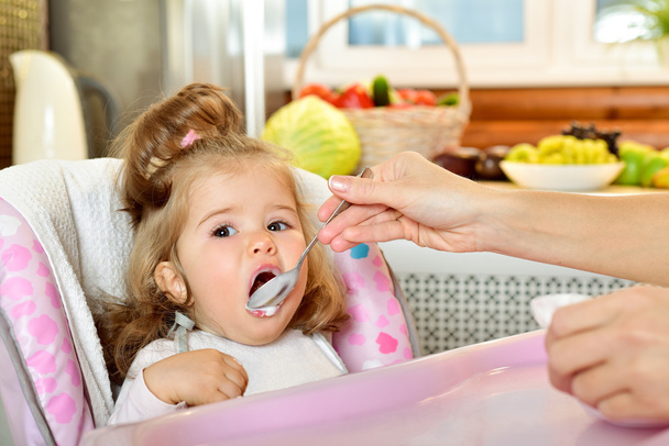 Mother spoon-feeds her child - Foto, Bild