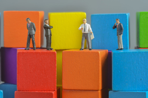Miniature people on stack of colorful wooden cube building block - Photo, image