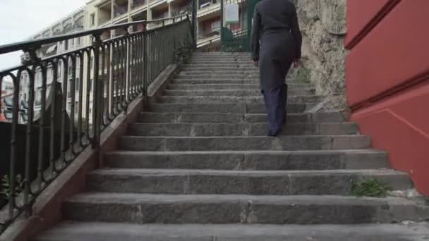 Vrouw gaan omhoog trappen jas dragen in de stad achterzijde terug weergave. - Video